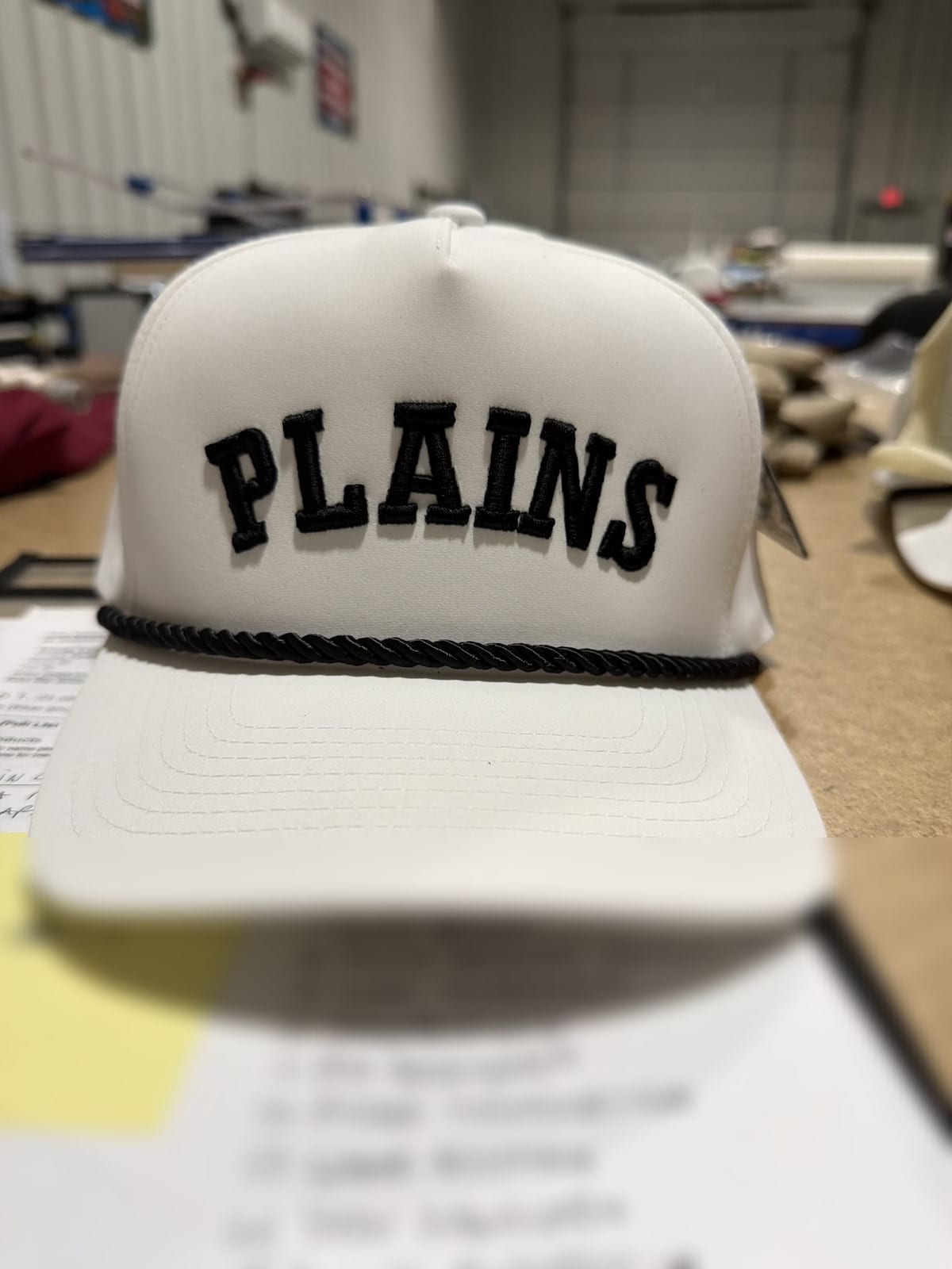 Puff-embroidered Plains cap sitting on a handwritten customer order list