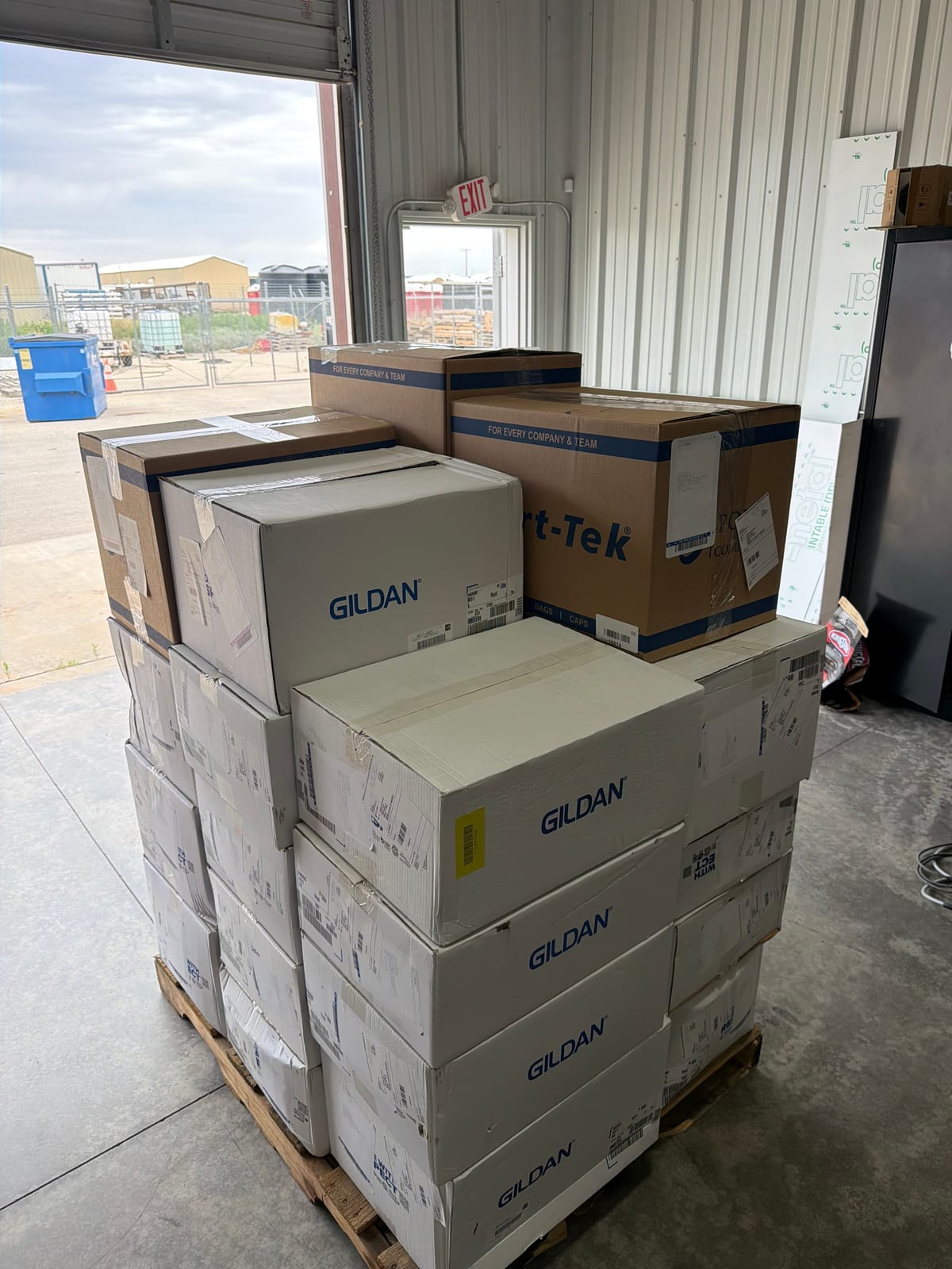 Pallet of Gildan and Sport-Tek blank apparel cases in the warehouse